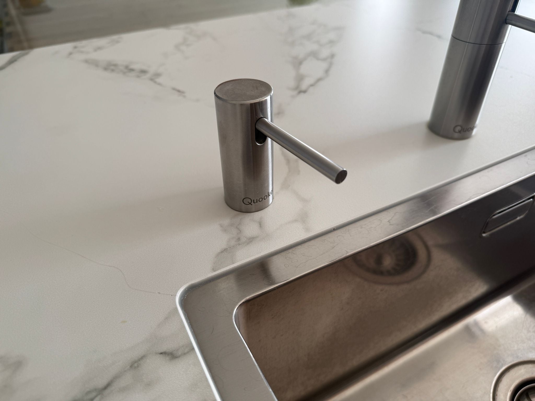 Tweedehandse keuken in houtlook met een grijs kookeiland en kunststoffen blad en close up van quooker