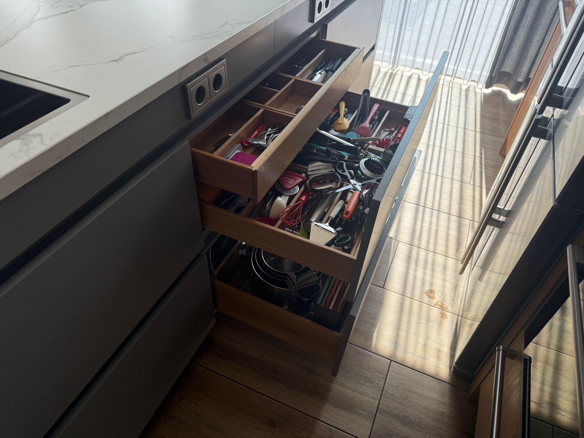 Tweedehandse keuken in houtlook met een grijs kookeiland en kunststoffen blad met lades die open staan