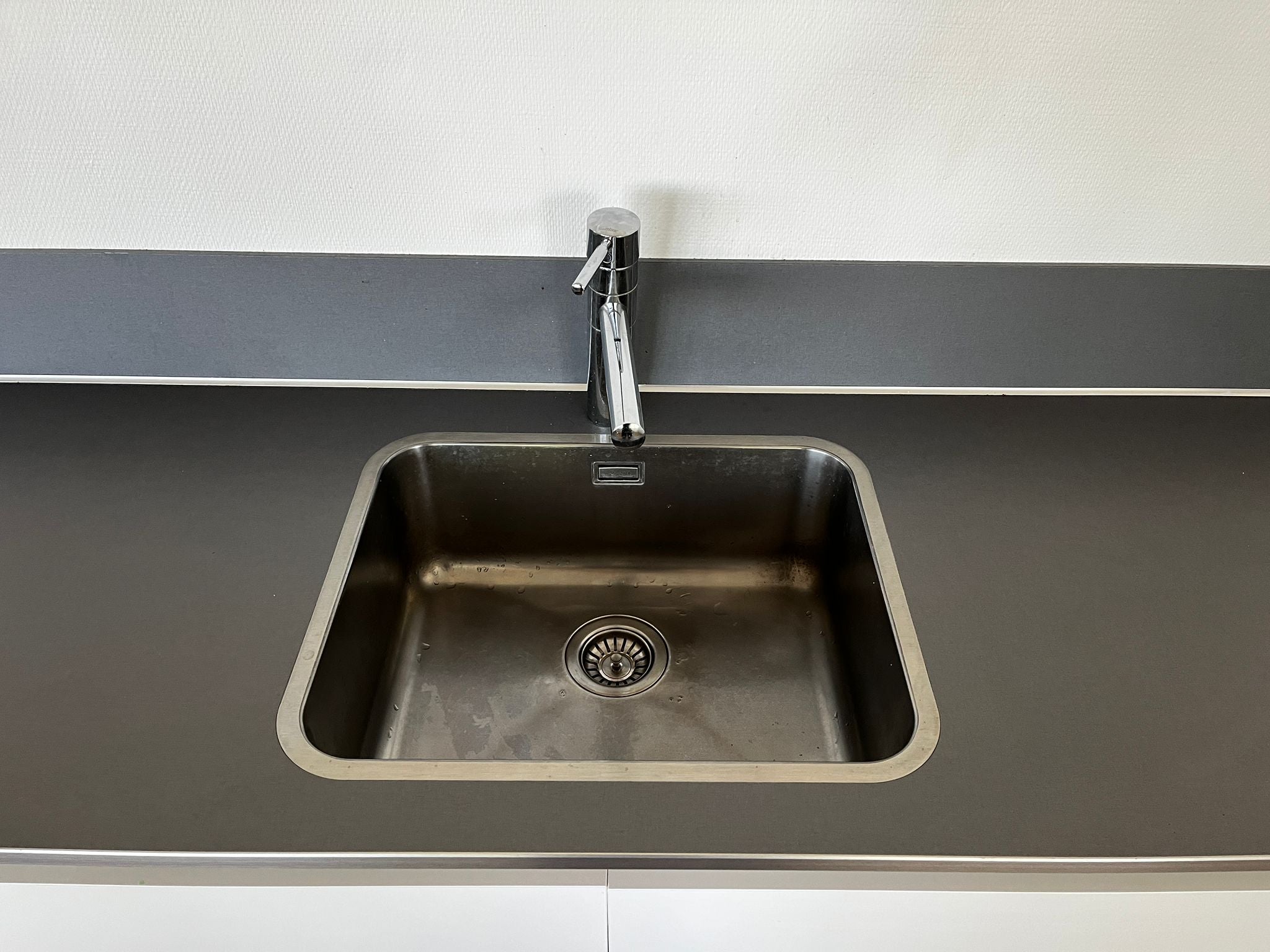 Witte hoekkeuken met ingebouwde AEG apparatuur met grijze wasbak