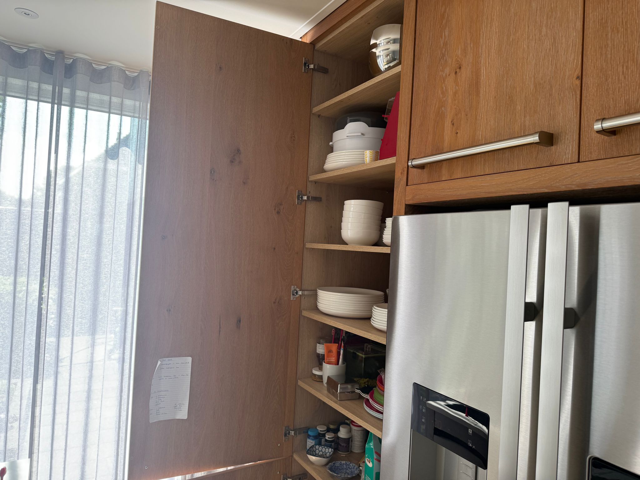 Tweedehandse keuken in houtlook met een grijs kookeiland en kunststoffen blad met openstaande houtlook keukenkastje