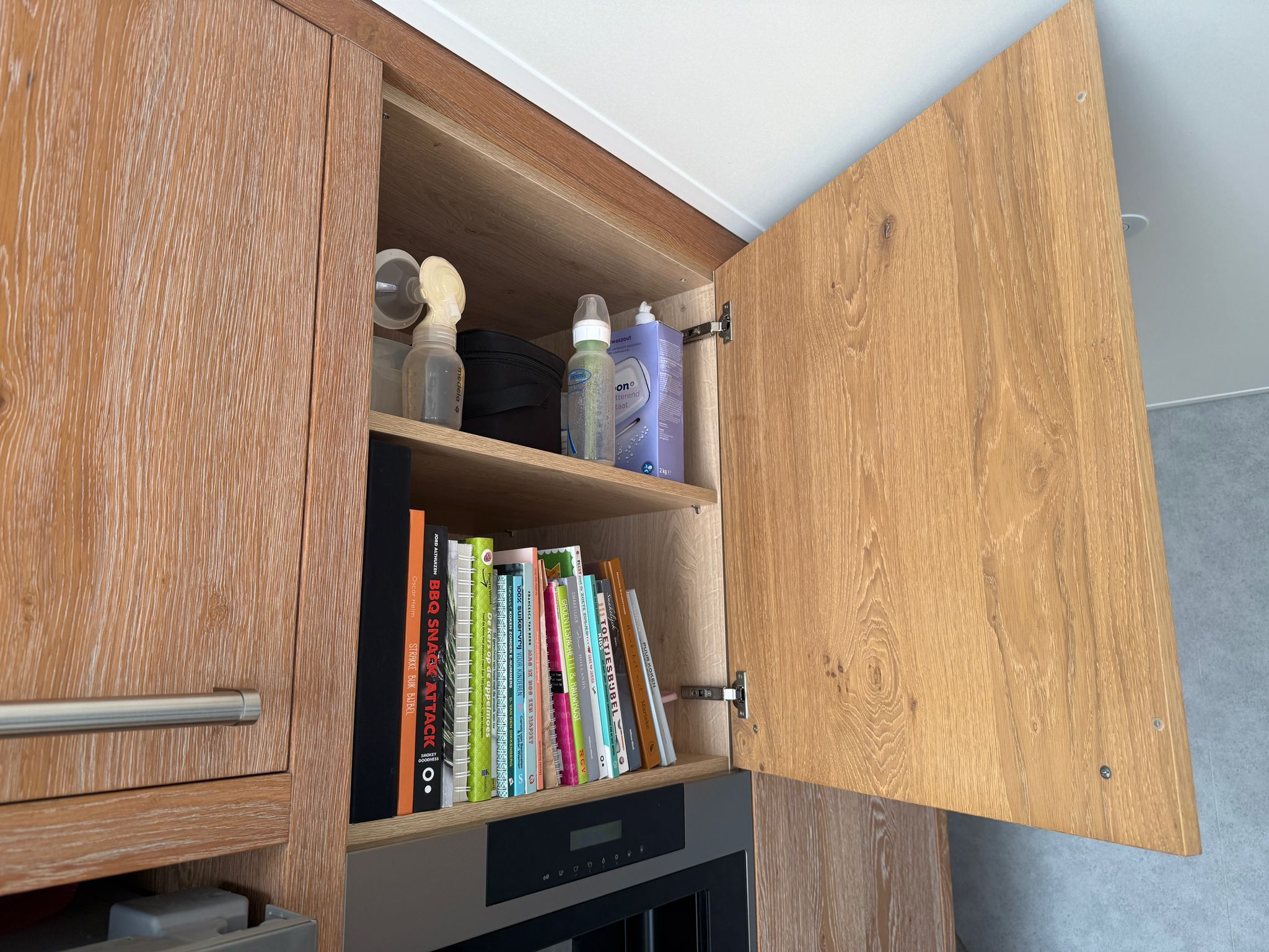 Tweedehandse keuken in houtlook met een grijs kookeiland en kunststoffen blad met een keukenkastje boven de inbouw apparatuur
