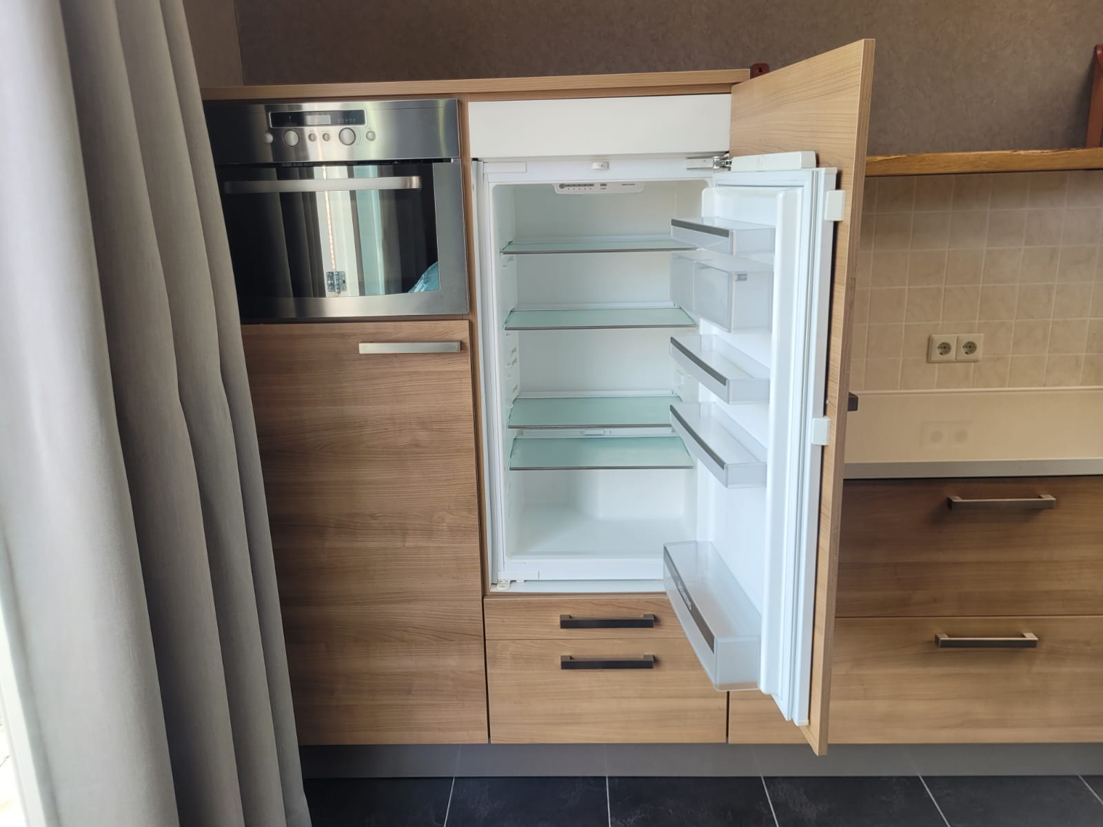 Rechte tweedehands keuken met houtkleur inclusief oven, magnetron en gasplaat met afzuigkap en koelkast die open staat