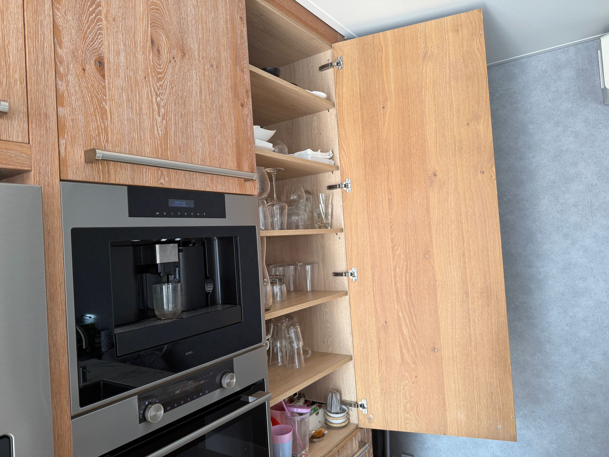 Tweedehandse keuken in houtlook met een grijs kookeiland en kunststoffen blad met kast naast de ovens