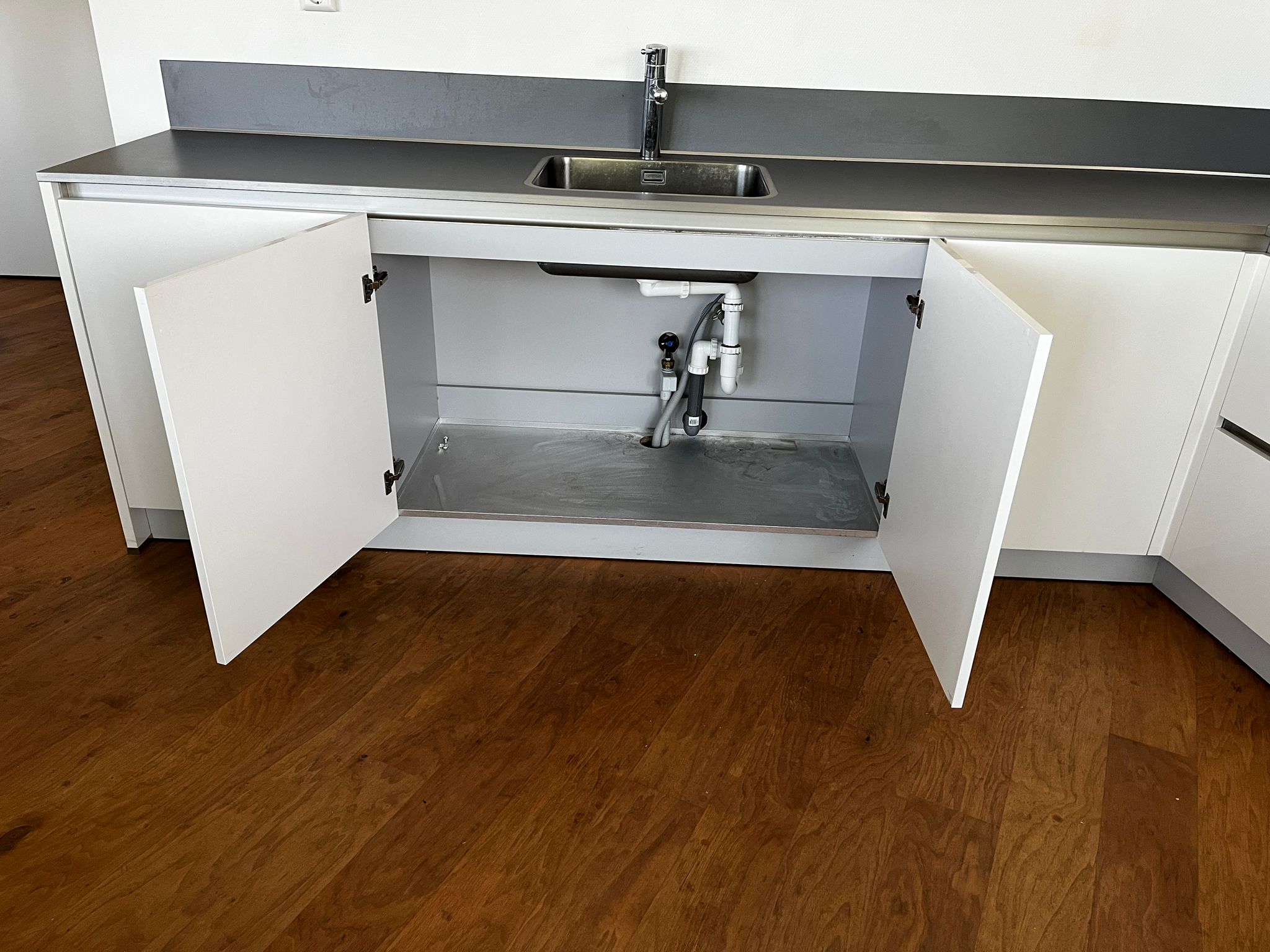 Witte hoekkeuken met ingebouwde AEG apparatuur met een grote kast onder de wasbak