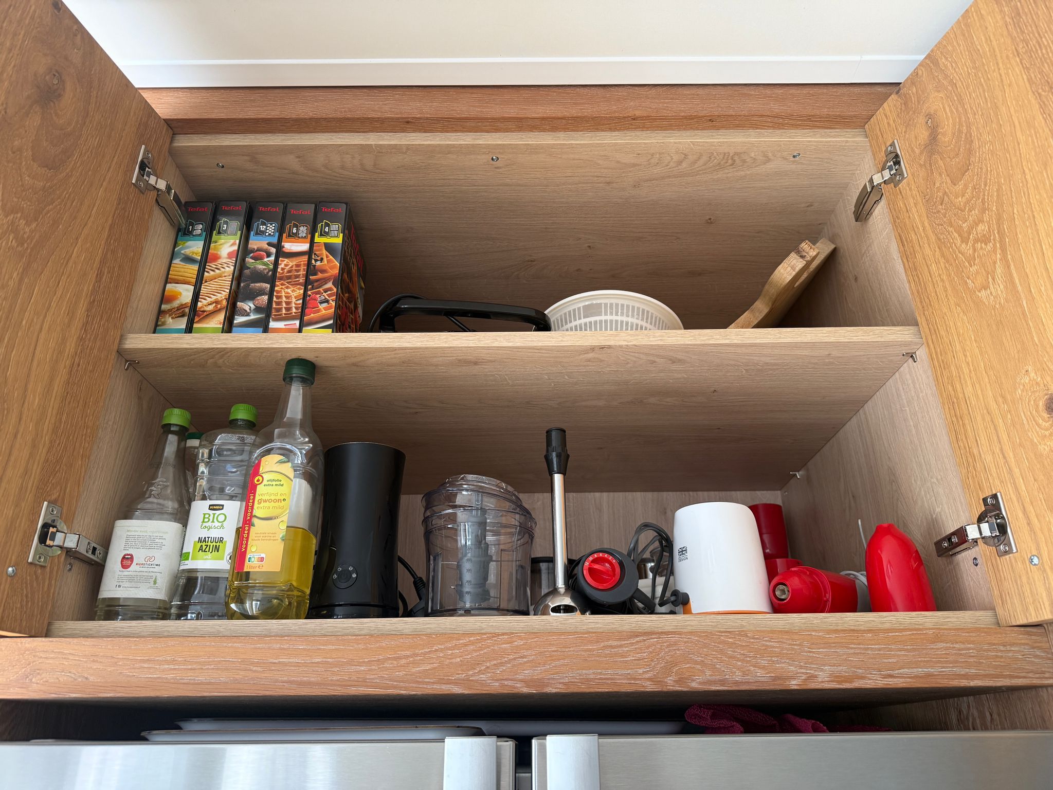 Tweedehandse keuken in houtlook met een grijs kookeiland en kunststoffen blad met een kast boven de koelkast