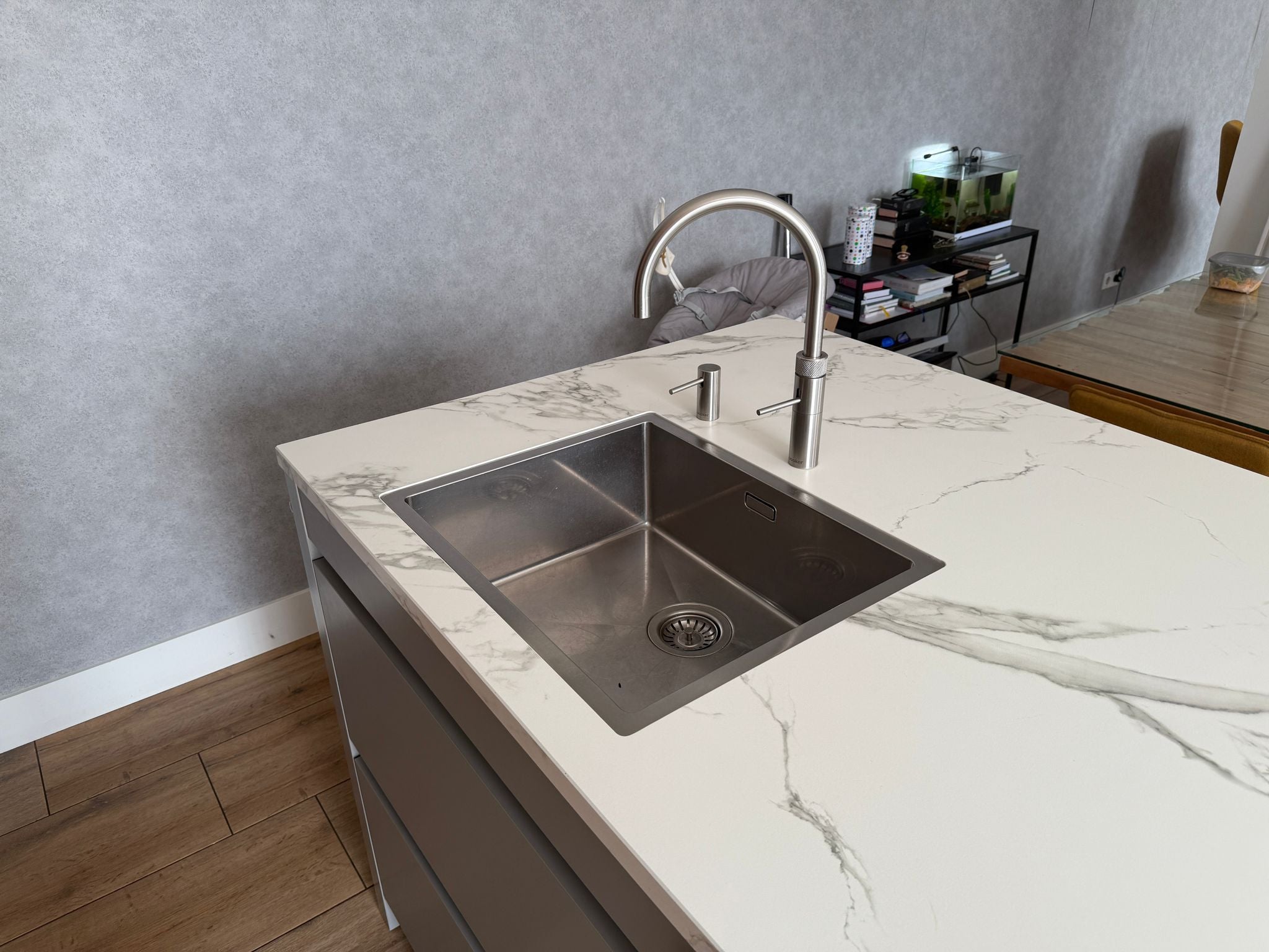 Tweedehandse keuken in houtlook met een grijs kookeiland en kunststoffe blad en metalen wasbak met quooker