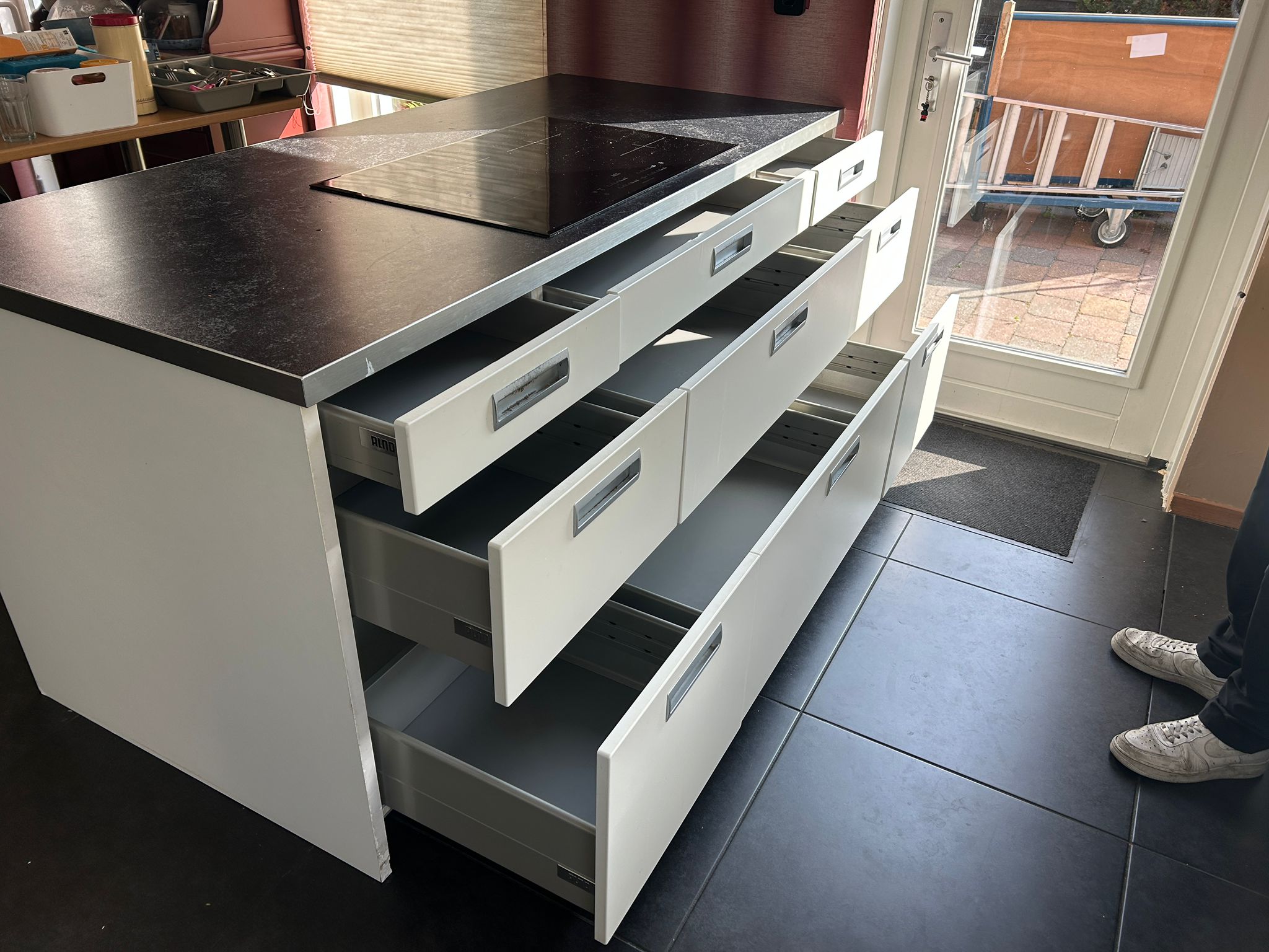 Witte tweedehandse keuken van het merk Alno met een wit schiereiland met lades die open staan