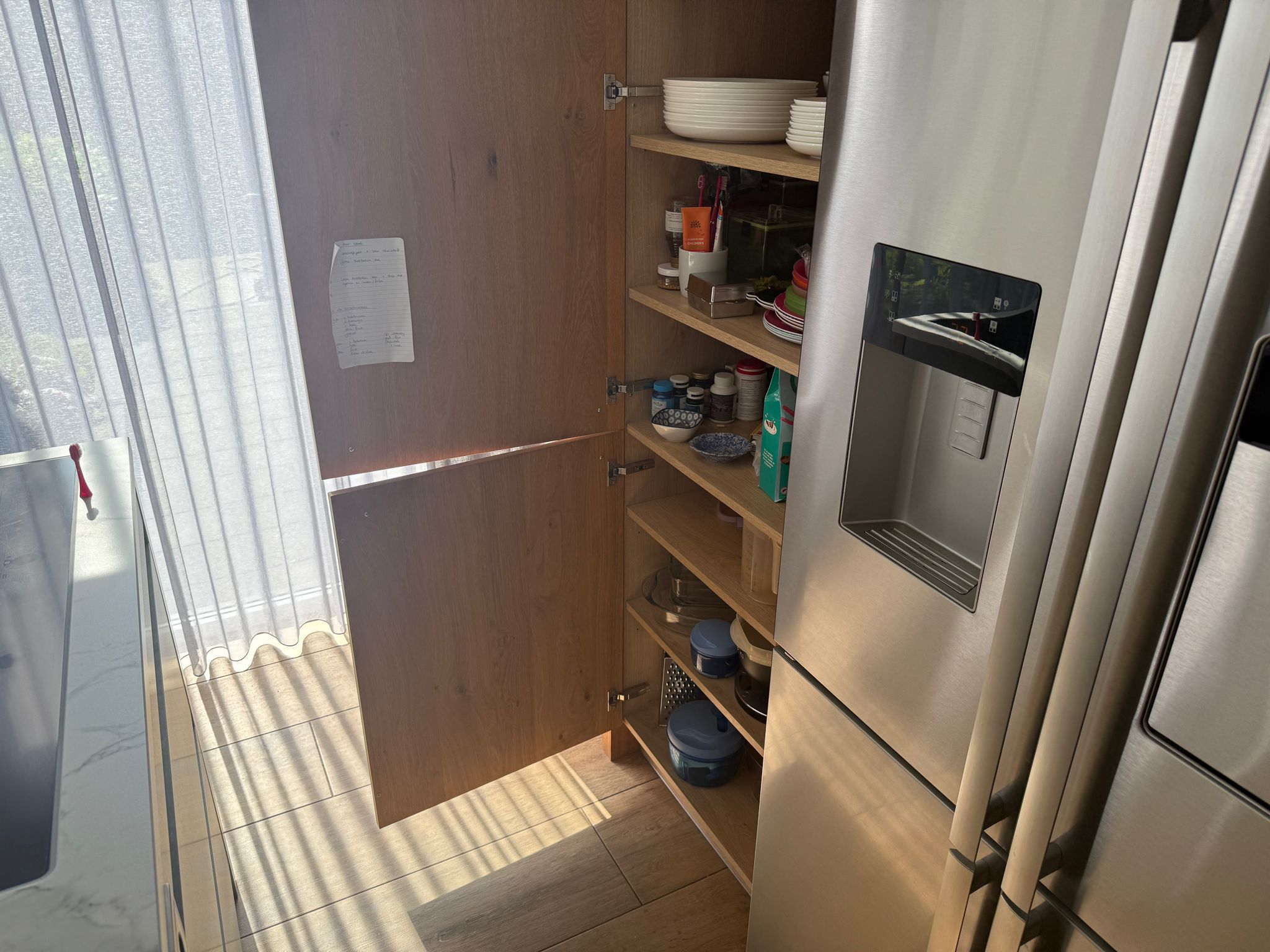 Tweedehandse keuken in houtlook met een grijs kookeiland en kunststoffen blad openstaande kast
