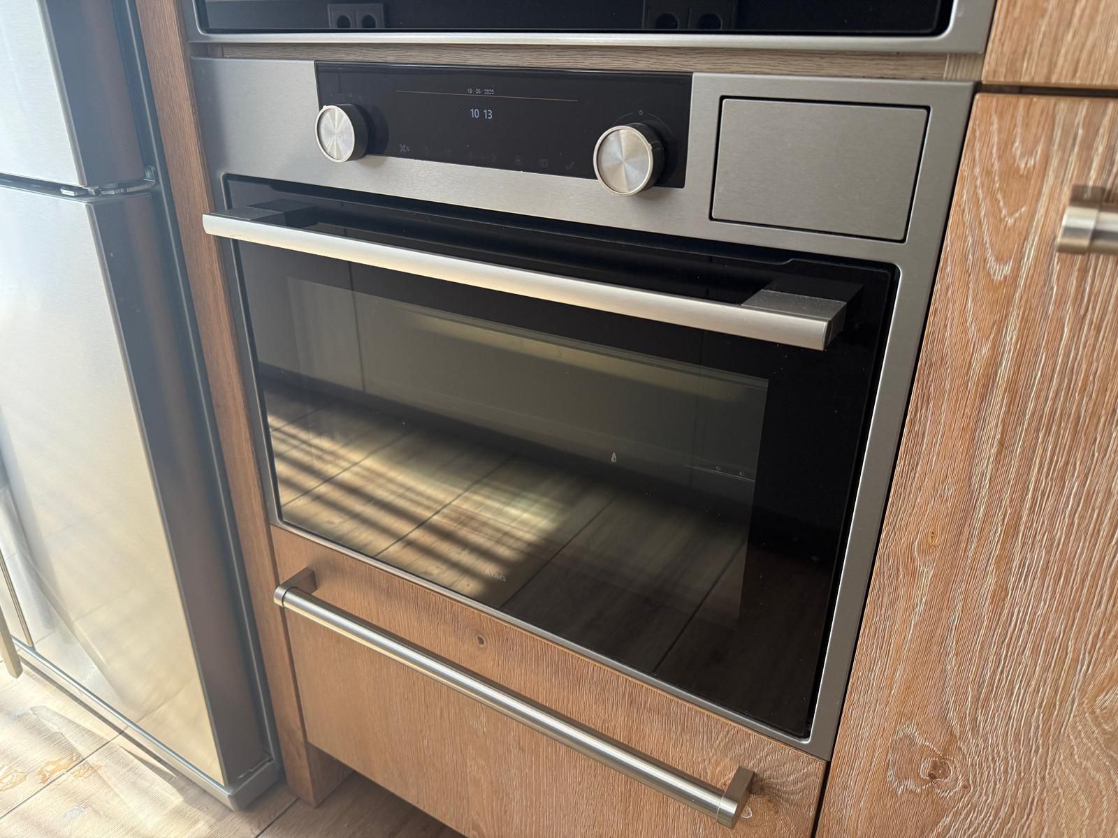 Tweedehandse keuken in houtlook met een grijs kookeiland en kunststoffen blad met twee ingebouwde ovens