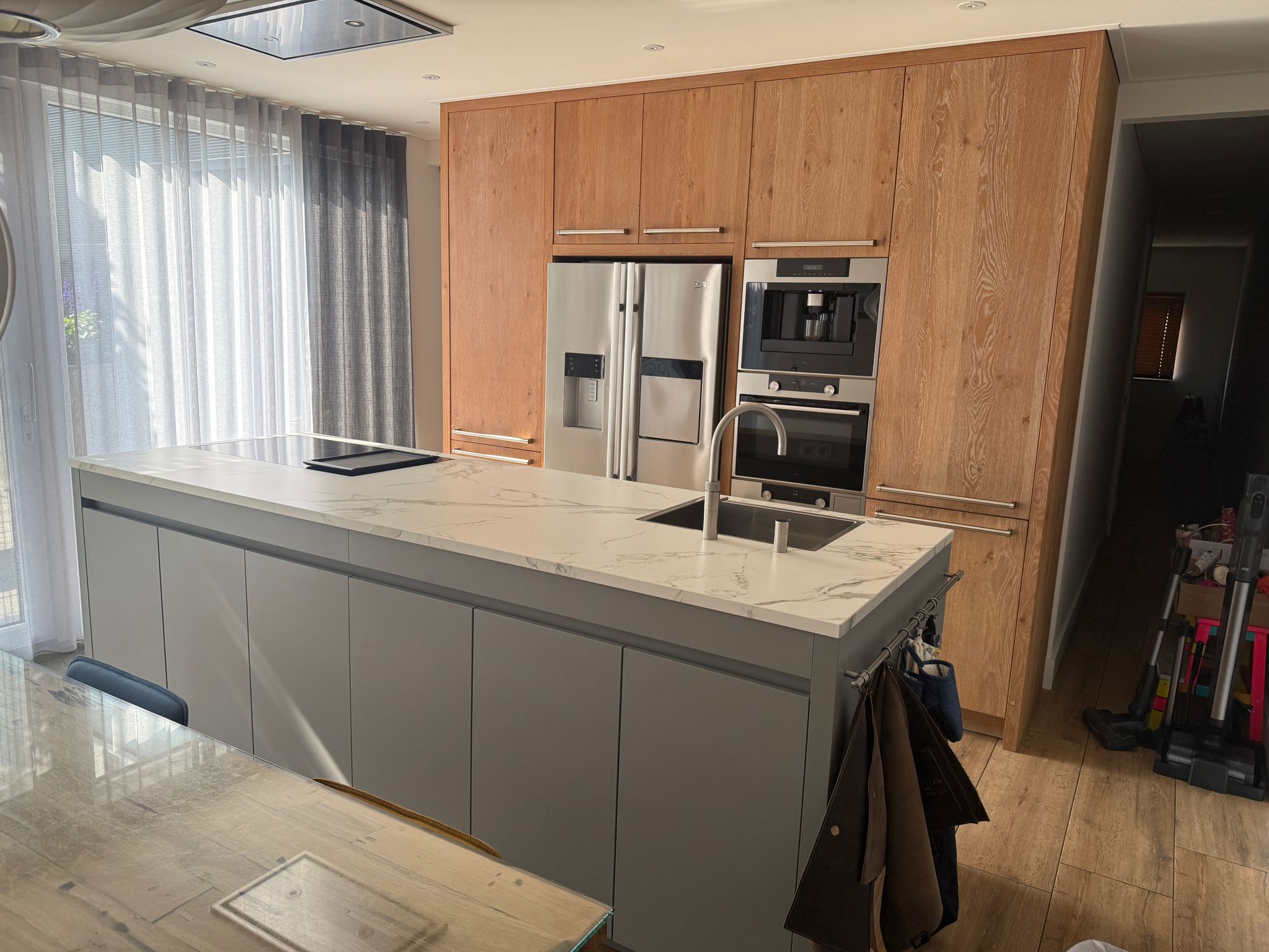 Tweedehandse keuken in houtlook met een grijs kookeiland en kunststoffe blad van andere hoek