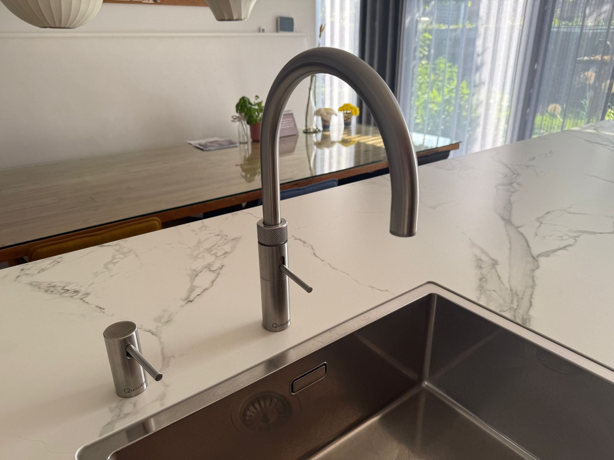 Tweedehandse keuken in houtlook met een grijs kookeiland en kunststoffen blad en zijkant van quooker