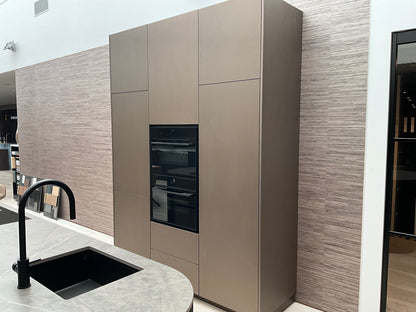 Showroomkeuken van het merk Kembra met kookeiland van zwart hout met champagne brons blad en keuken kasten met twee ovens