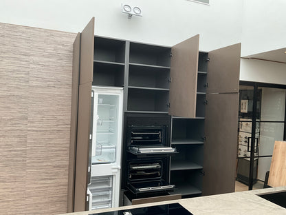 Showroomkeuken van het merk Kembra met kookeiland van zwart hout met champagne bronzen kasten die open staan