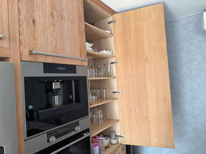 Tweedehandse keuken in houtlook met een grijs kookeiland en kunststoffen blad met kast naast de ovens