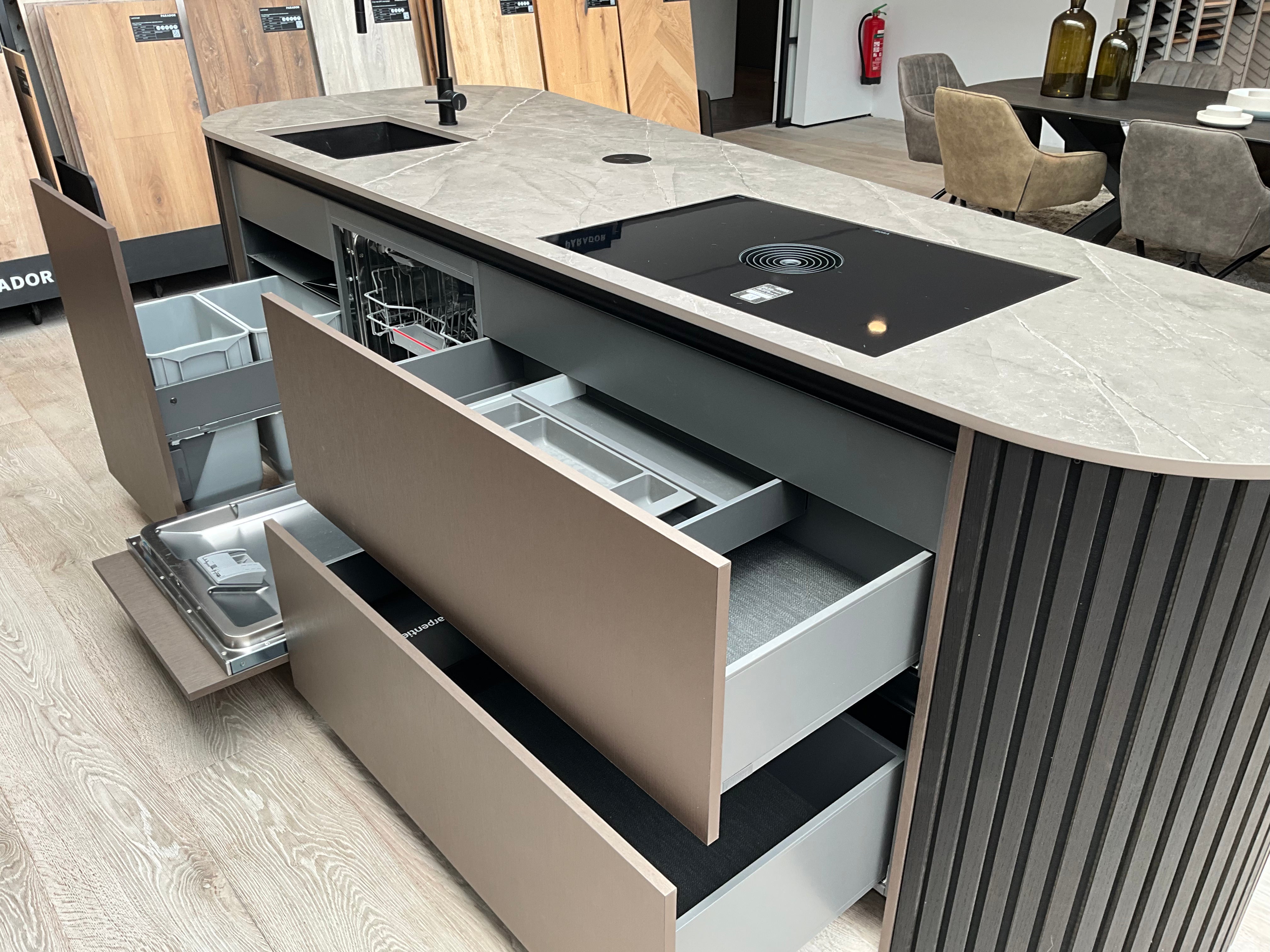 Showroomkeuken van het merk Kembra met kookeiland van zwart hout met champagne bronze kasten en lades