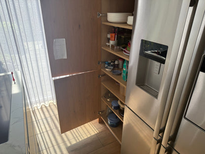 Tweedehandse keuken in houtlook met een grijs kookeiland en kunststoffen blad openstaande kast