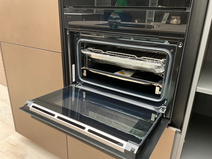 Showroomkeuken van het merk Kembra met kookeiland van zwart hout met champagne bronze blad met oven