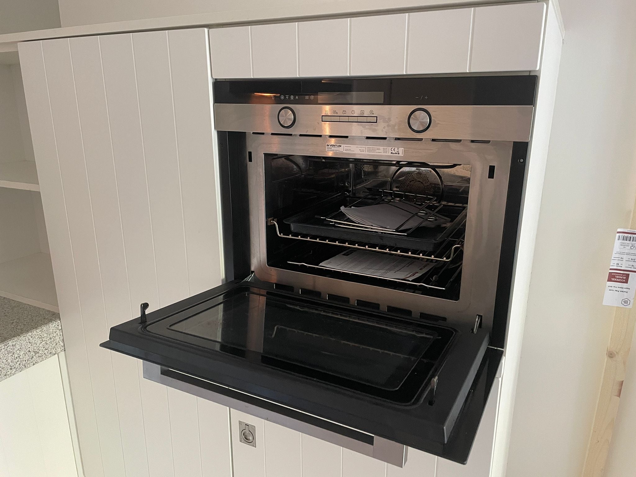 Tweedehands Bruynzeel hoekkeuken in het wit met een werkblad van graniet met een oven die open staat op de foto