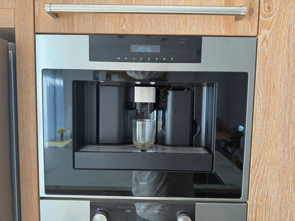 Tweedehandse keuken in houtlook met een grijs kookeiland en kunststoffen blad met koffieapparaat voorkant